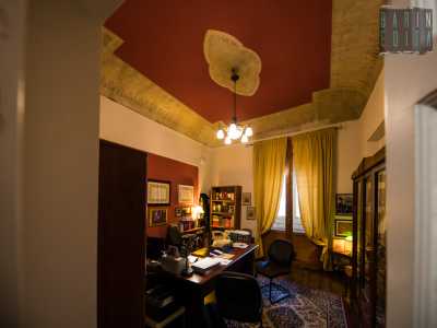 Sulle nostre teste si staglia una volta affrescata con lo stesso rosso brillante che caratterizza la facciata del palazzo...